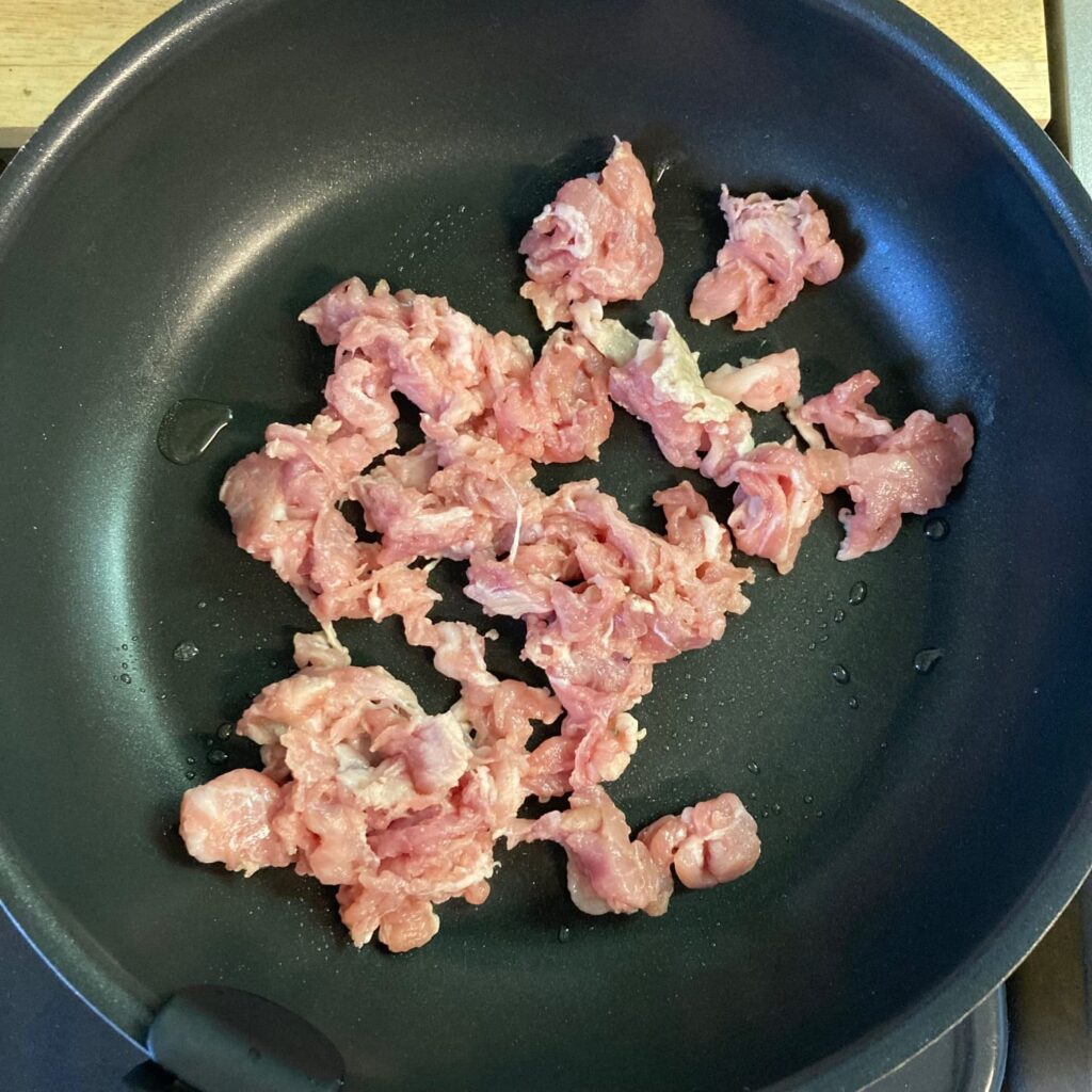 ほぐした豚肉が入ったフライパン