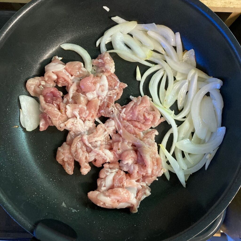 端によせた玉ねぎと豚肉が入ったフライパン