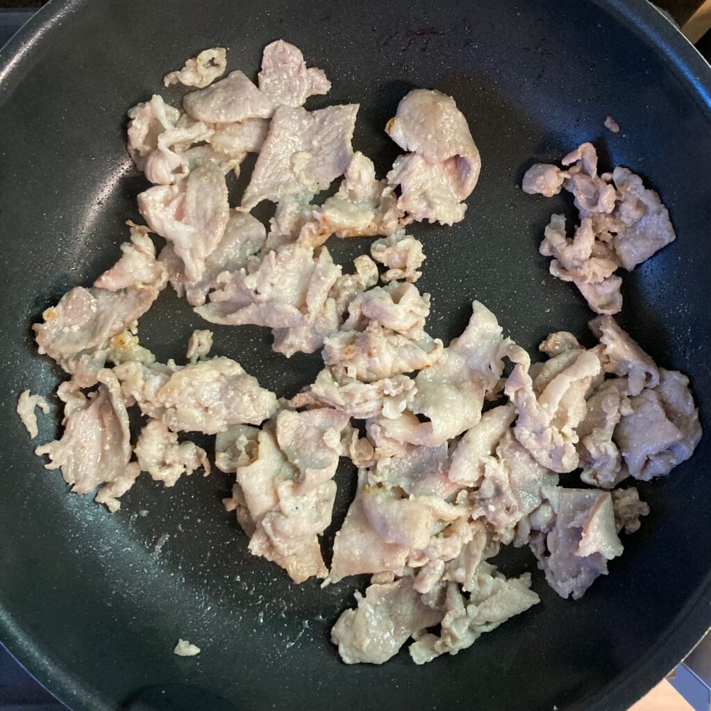 炒め途中の豚肉が入ったフライパン