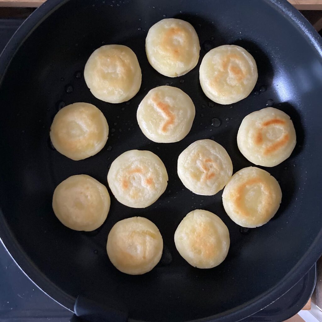 フライパンで焼いている焼き色がついた芋もち12個