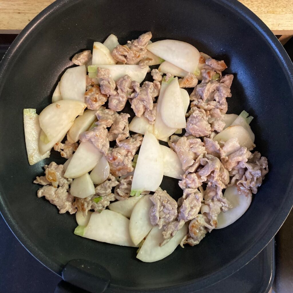 豚肉と焼き色がついたカブが入っているフライパン