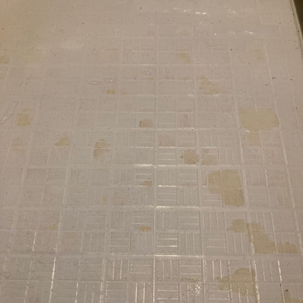 茶色っぽい水垢が目立つ掃除前の風呂場の床